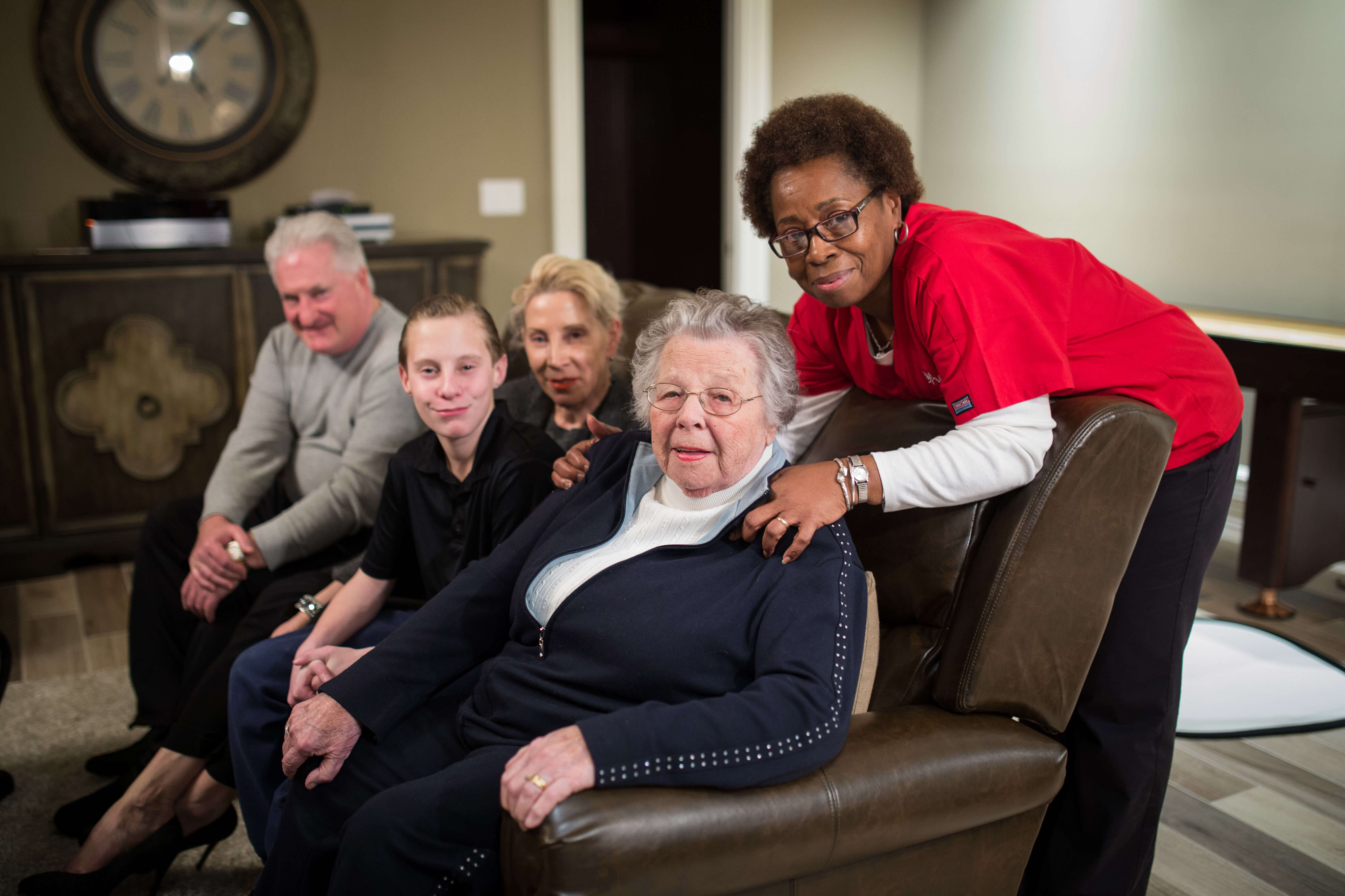 An aide who provides respite care to a senior poses with the senior and their family.