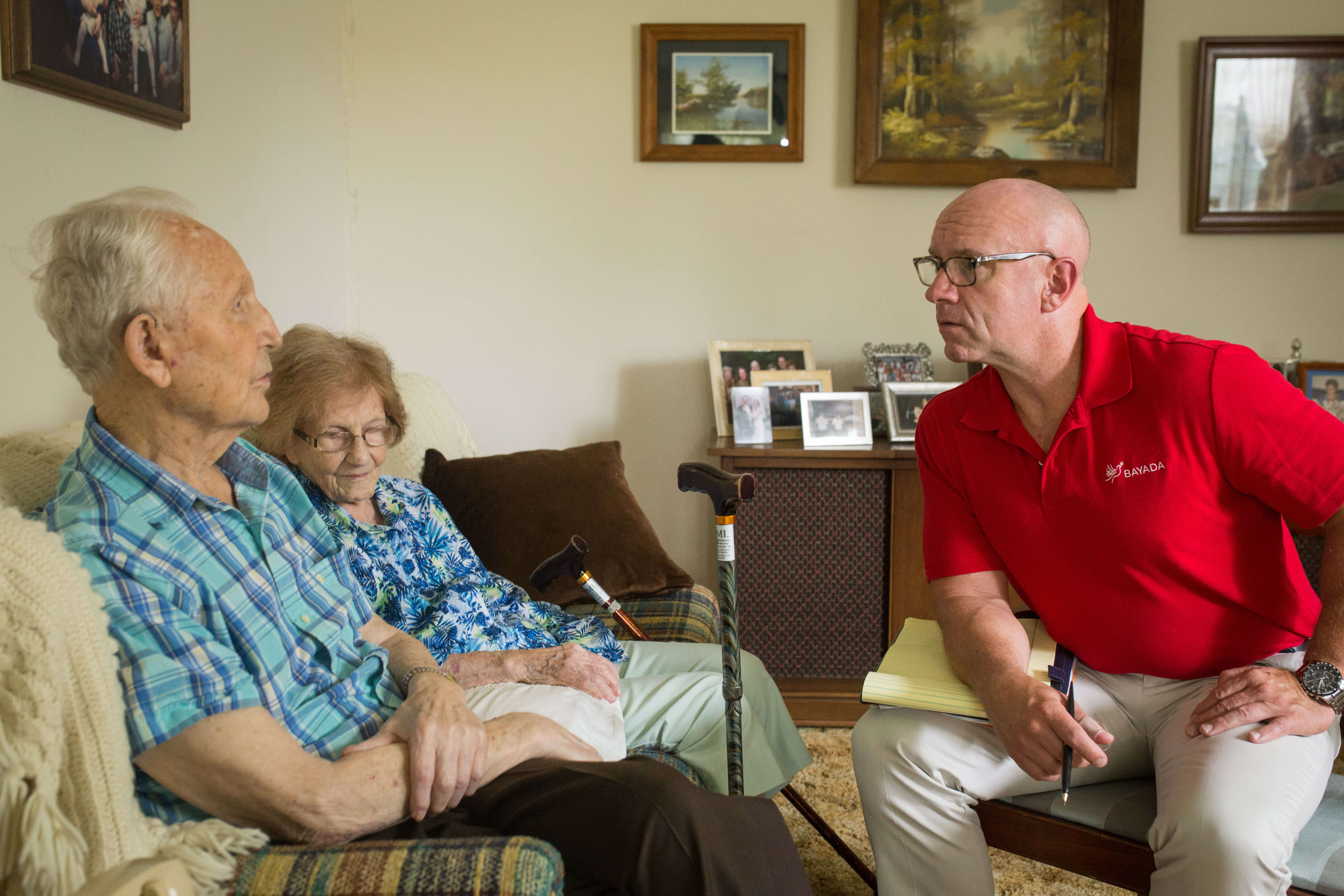 Stephen, a hospice social worker, speaks to his hospice client in his living room.