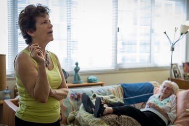 Caring for elderly parents: family caregiver speaks while parent is in background
